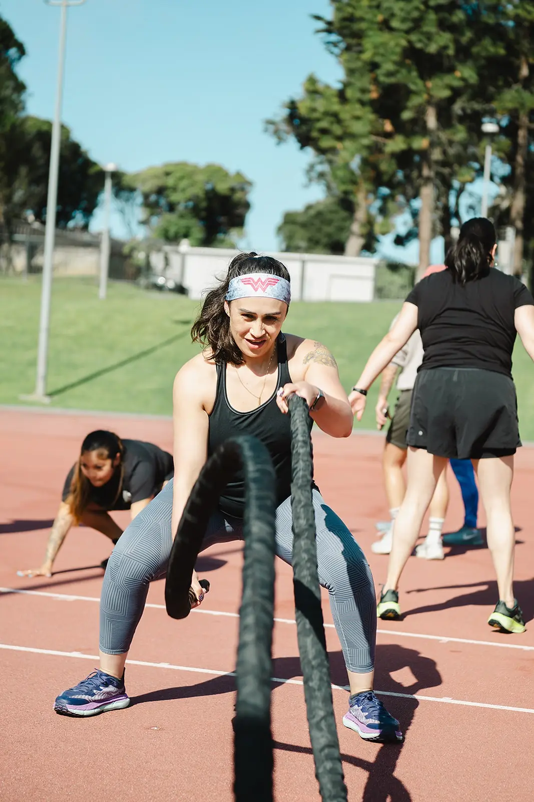 Athlete driving battle ropes during an outdoor conditioning circuit