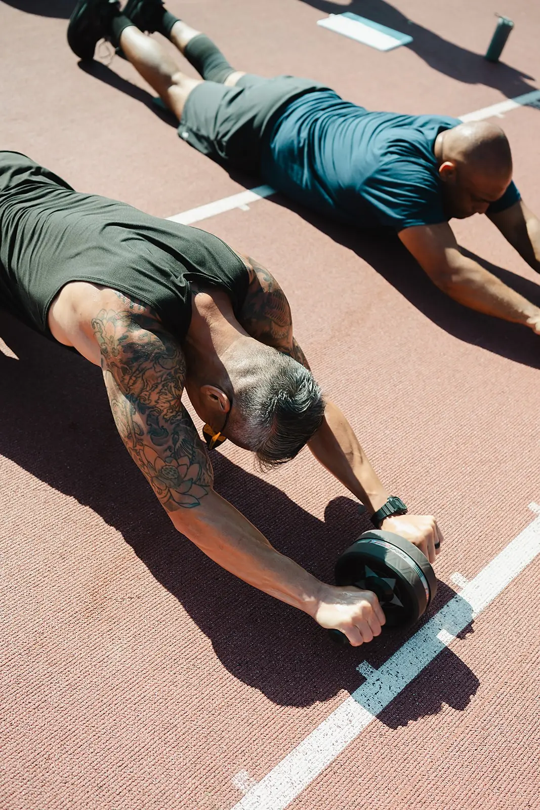 Overhead view of two members doing ab wheel rollouts on the track