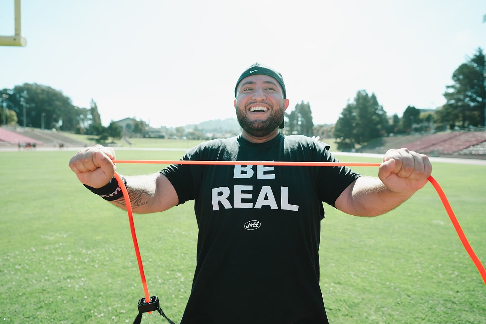 Member grinning while stretching a resistance band across the field