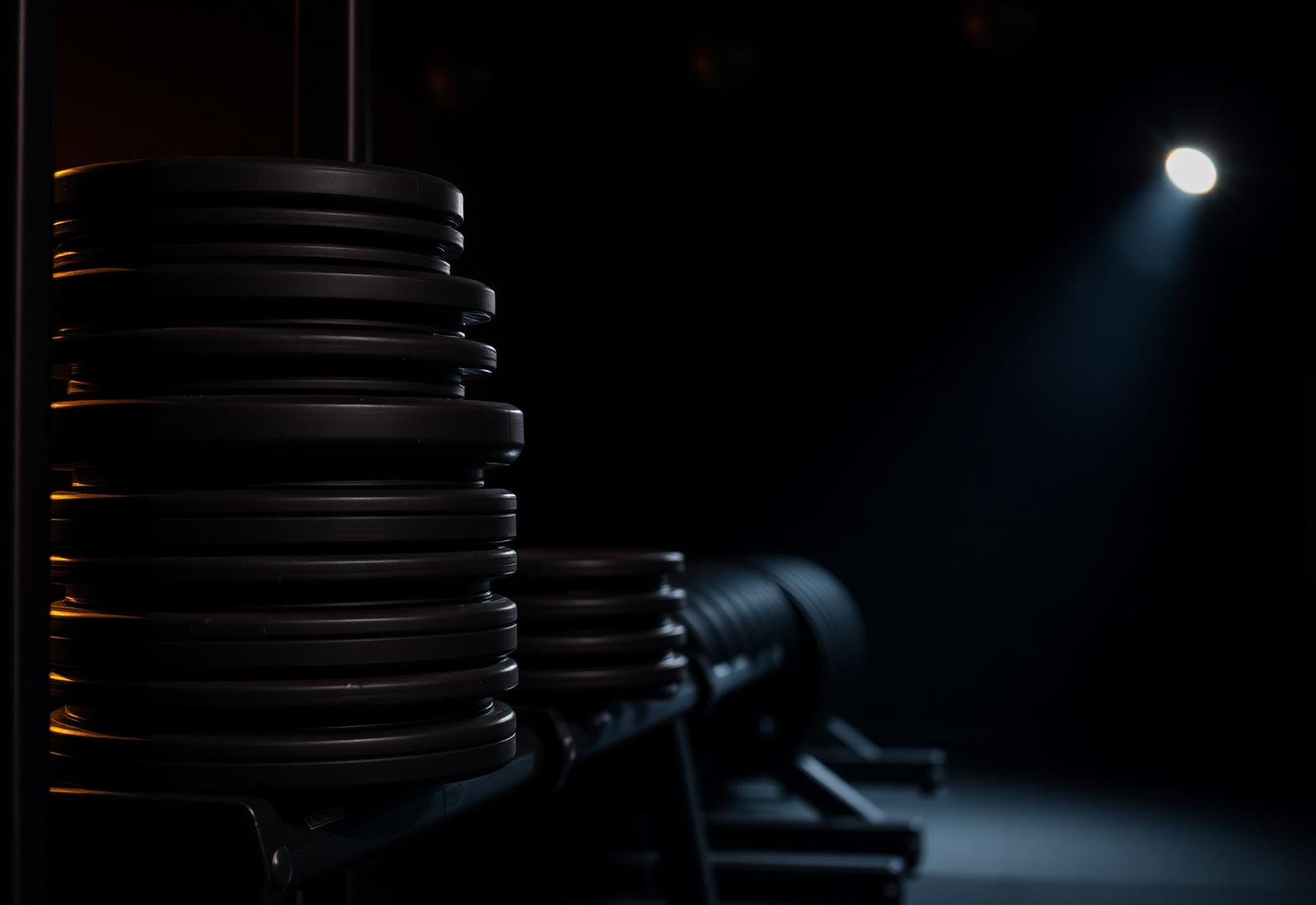 Stack of black weight plates lit from the side inside the Nanstop training floor